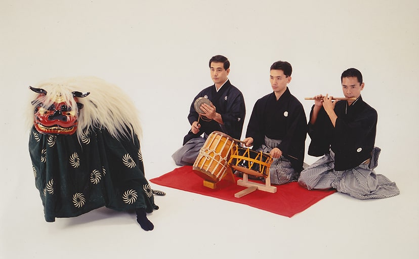 獅子舞を披露する演者と3名のお囃子演奏者の写真
