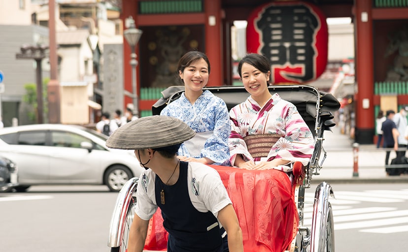 雷門前にて笑顔で人力車に乗車する女性2人の写真